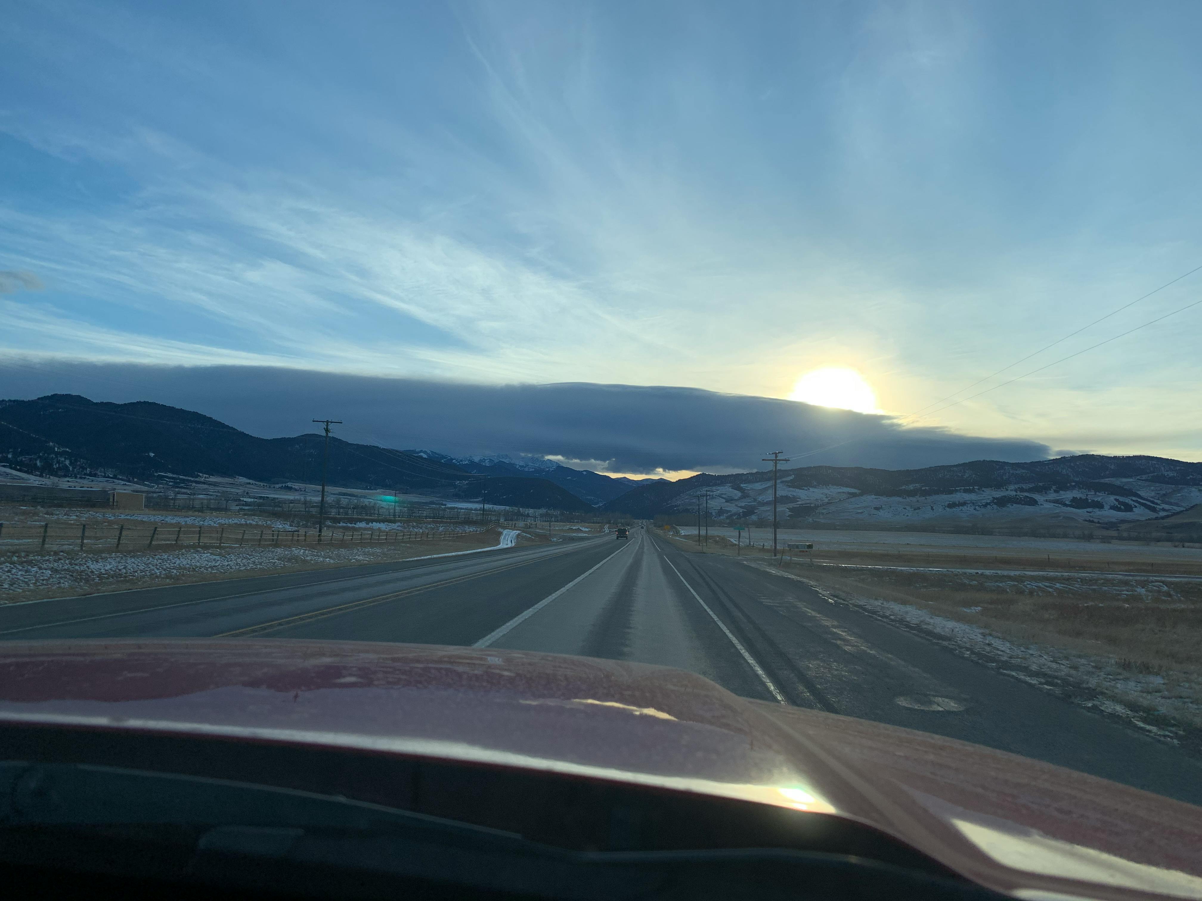 Taken from the passenger seat of a car, the author travels towards snowy hills and the low-lying sun. 