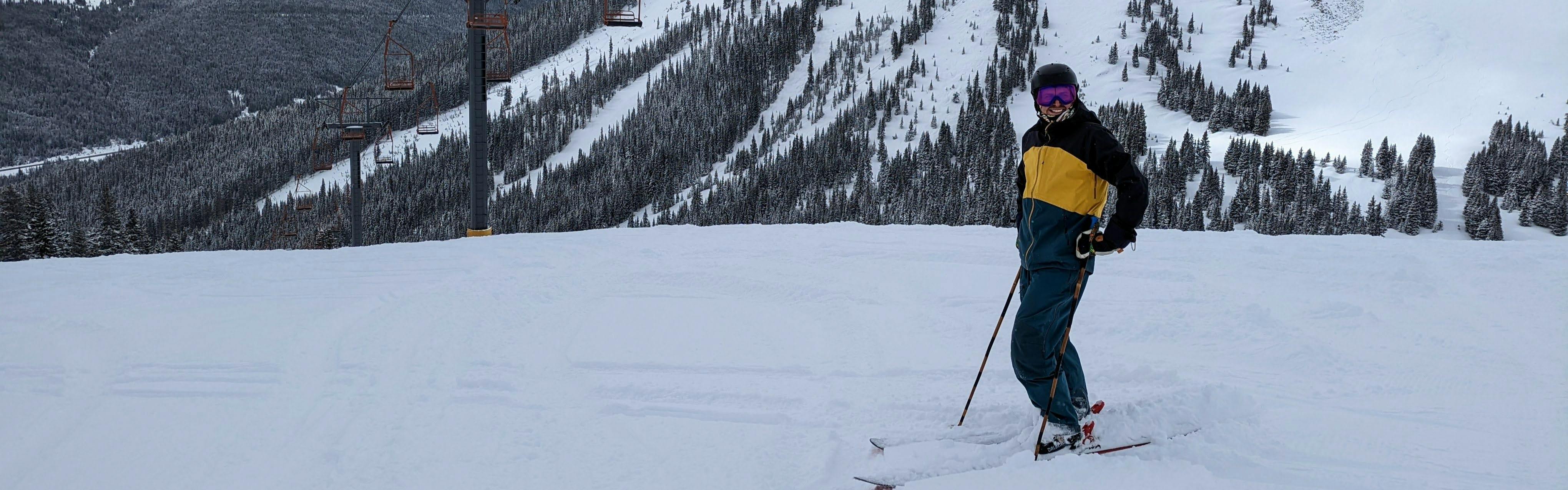 A man standing at the top of a ski run wearing the Flylow Men's Malone Shell Jacket.