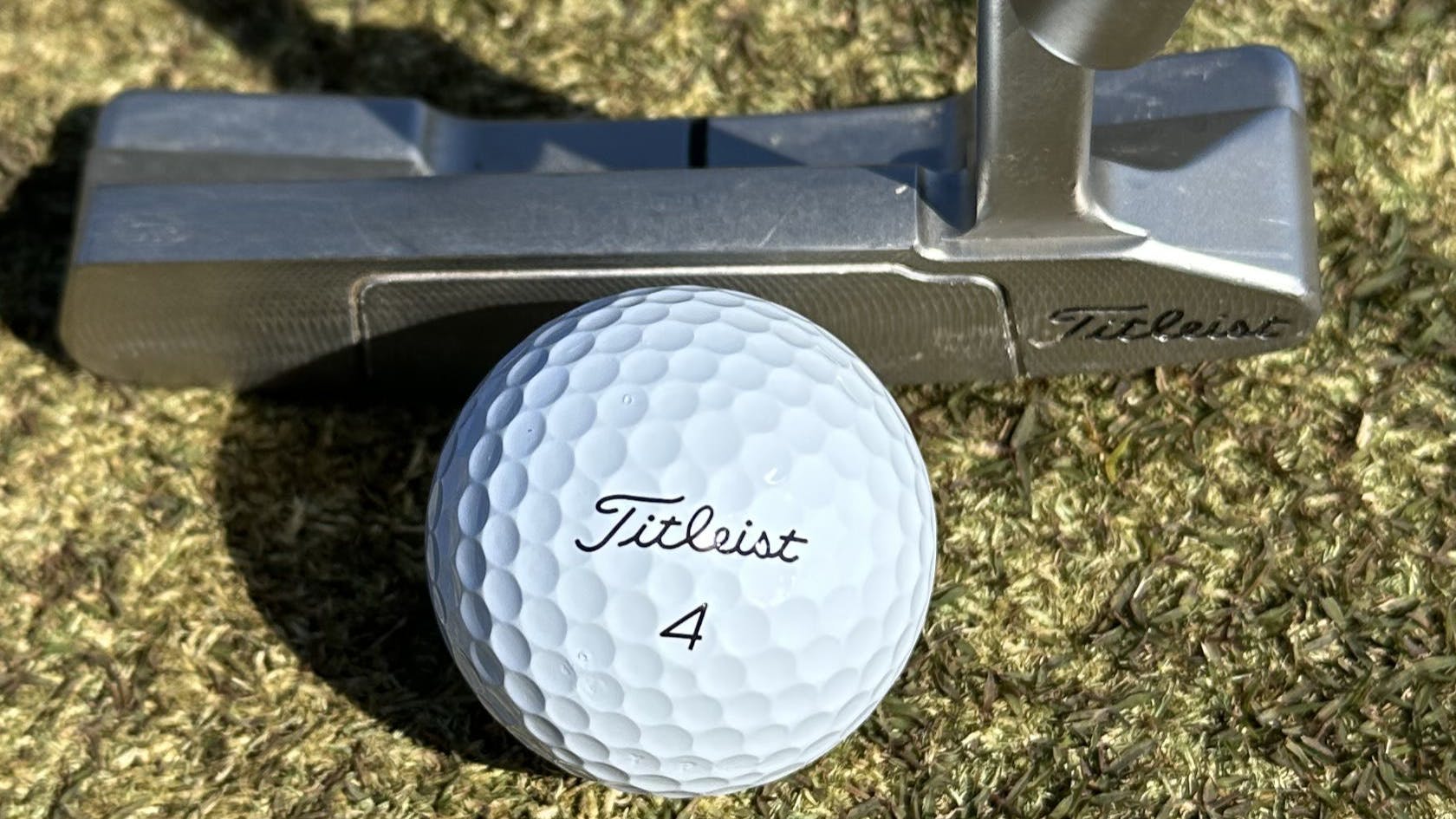 The  Titleist 2023 Pro V1 Golf Ball in front of a putter. 