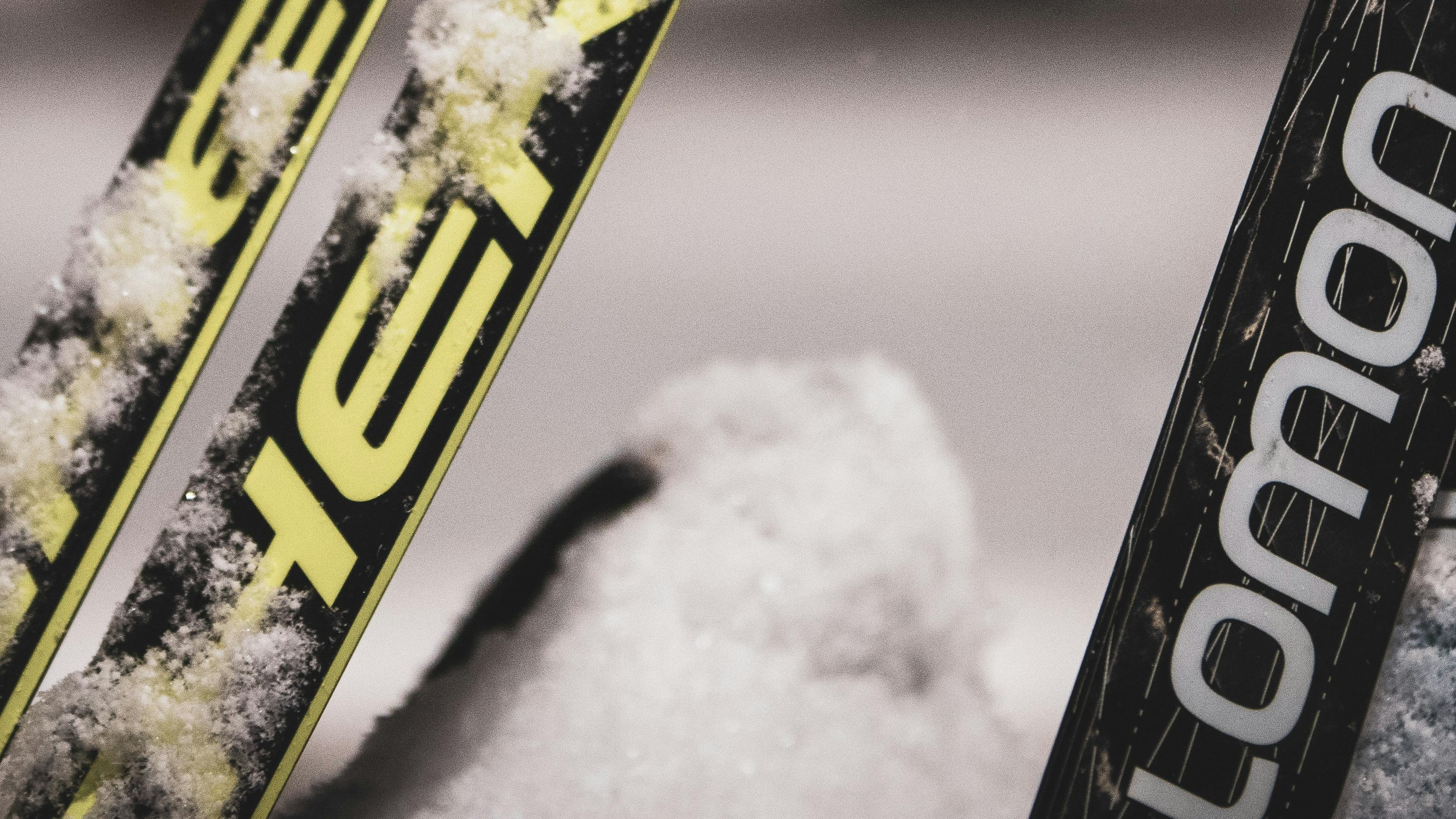 Closeup on two pairs of skis coated with snow