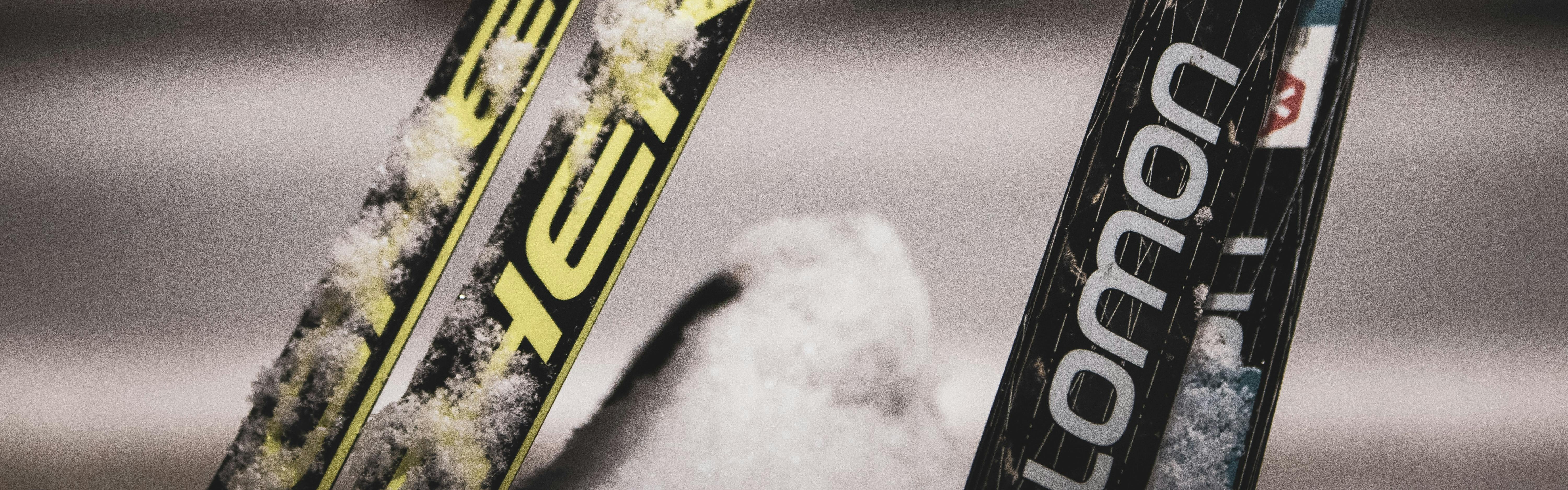Closeup on two pairs of skis coated with snow