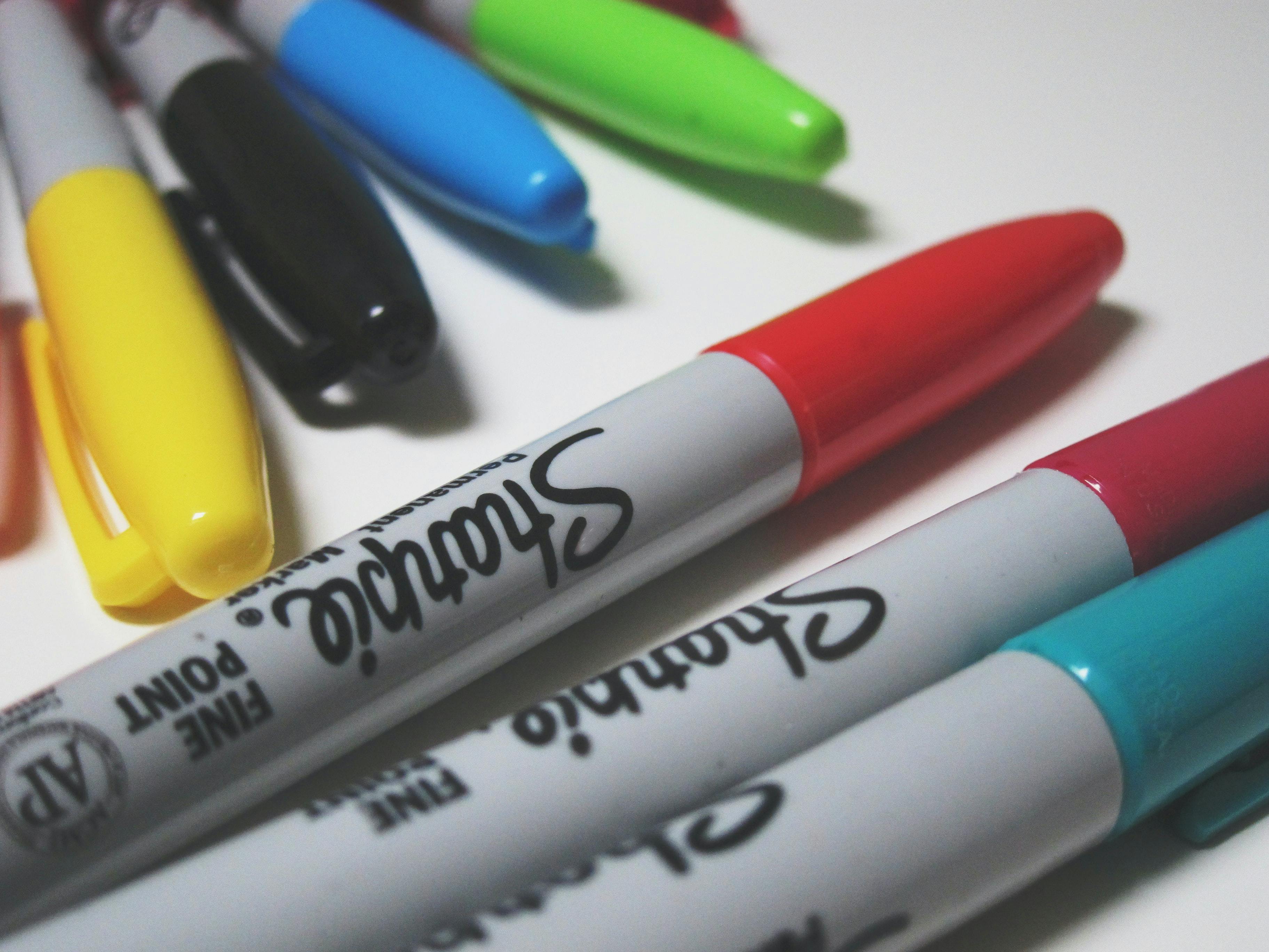 A close-up of several colorful Sharpies on a white background. 