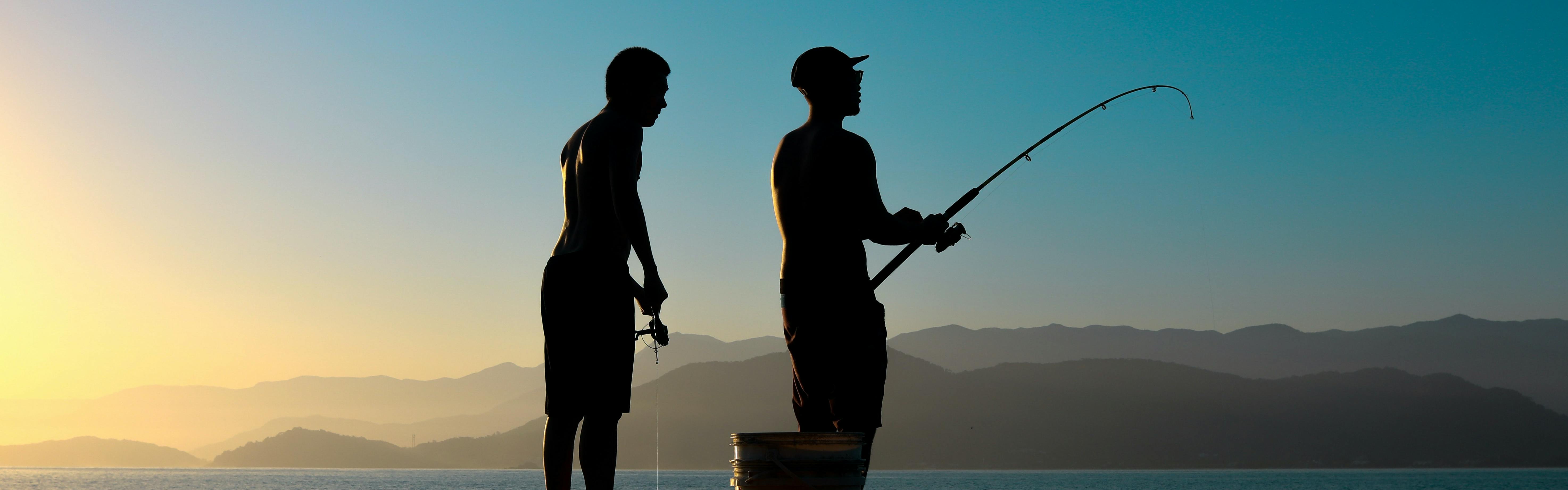 Two people standing on a pier fishing