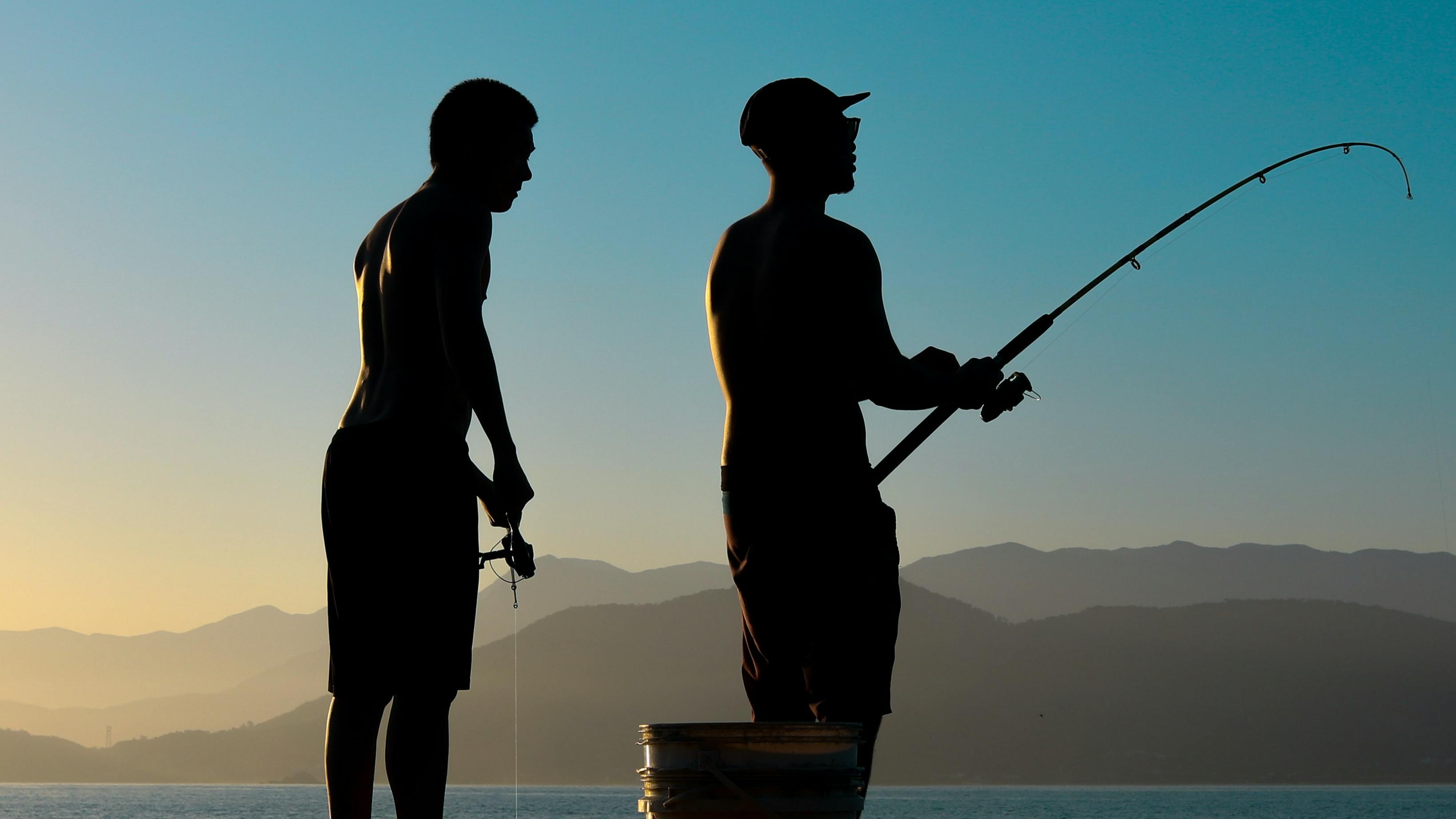 Two people standing on a pier fishing