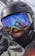 Snowboarder smiling with goggles, helmet, and facemask. 