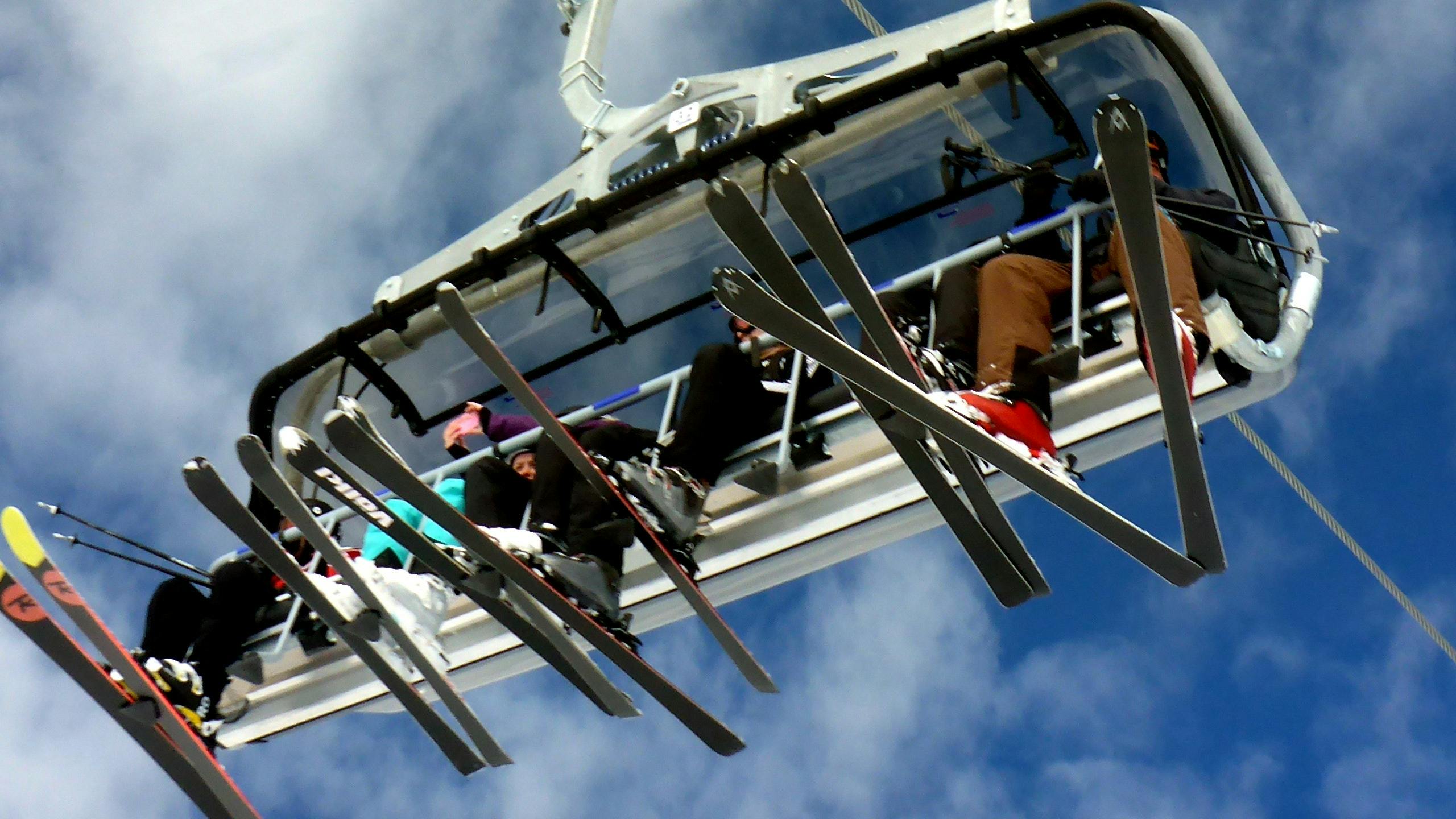 A view of skiers on a chairlift taken from below.
