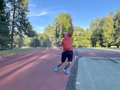 A man on a tennis court serving a ball with the Head Instinct MP 2022 Racquet.