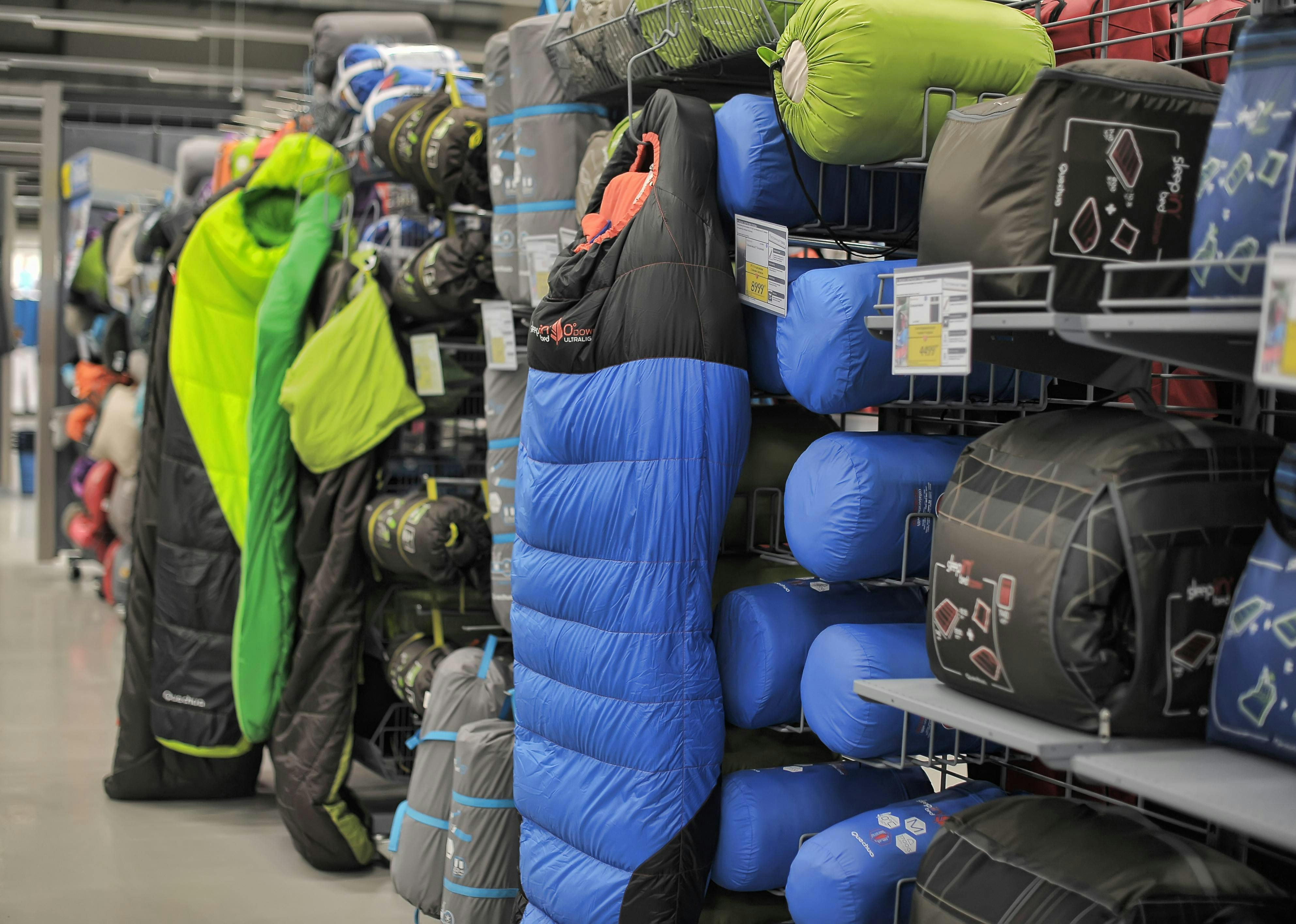 Sleeping bags line the shelf at an outdoor outfitters store. 