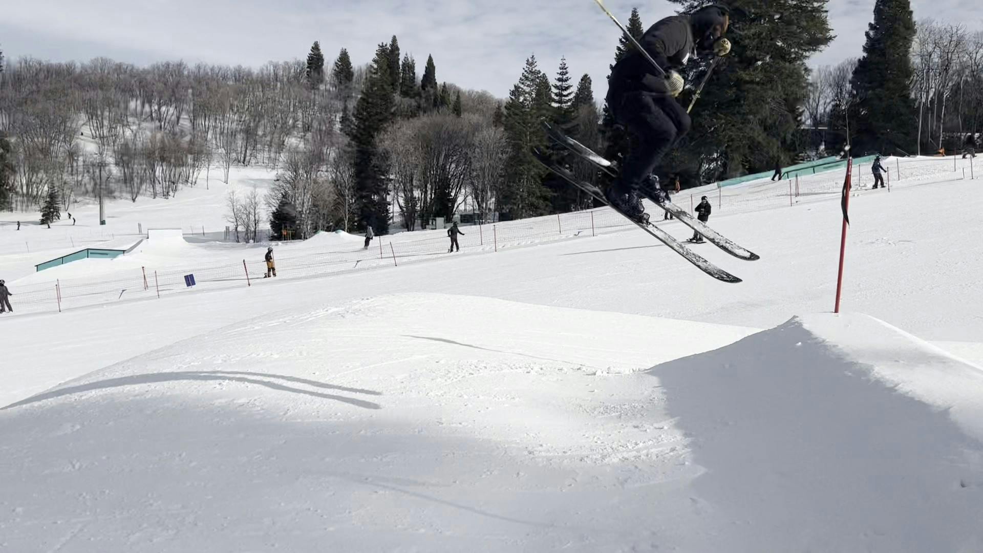 A skier jumping off a park feature on a ski run. 