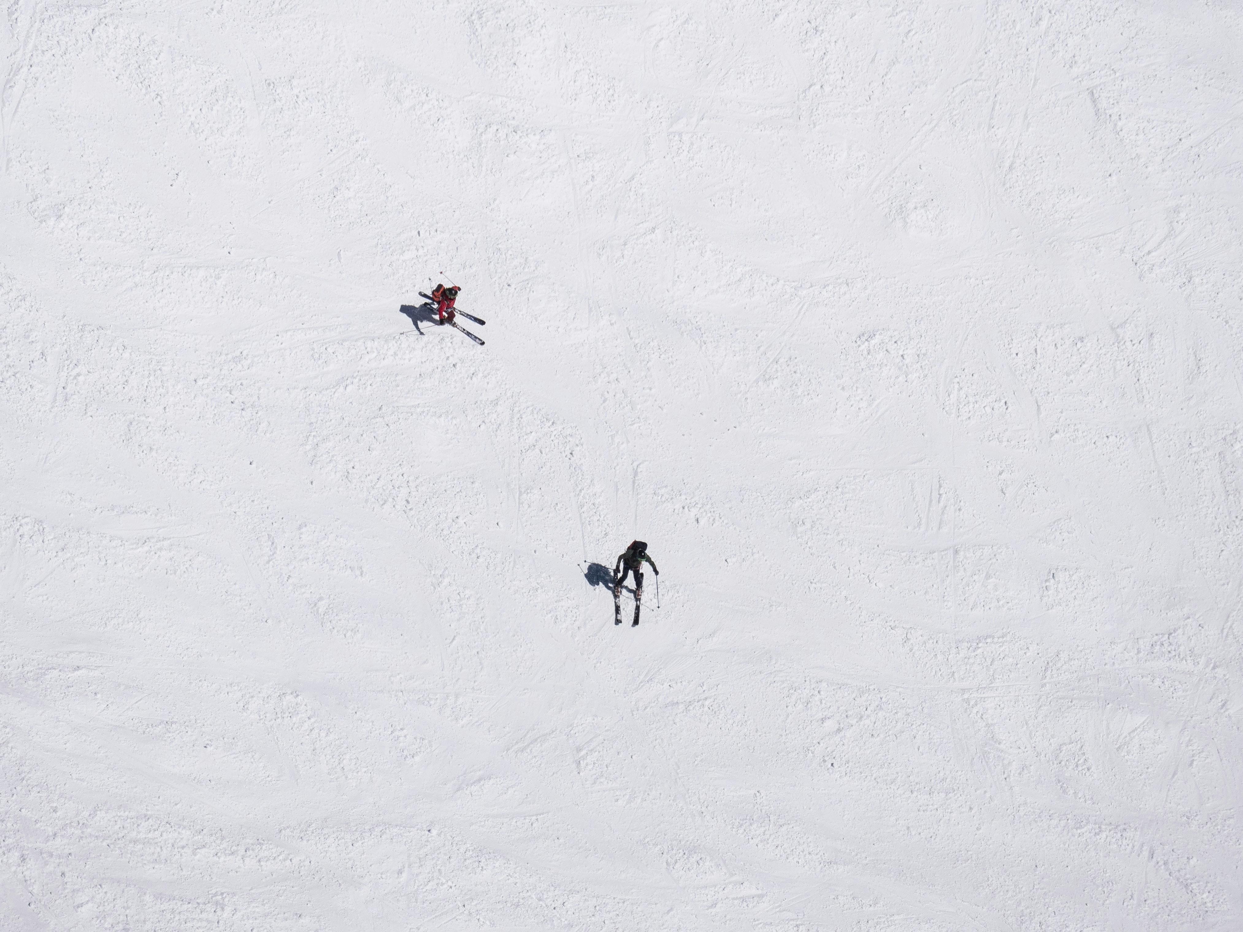 Ariel view of two skiers turning down a run. 