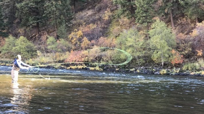 Curated expert Andrew S. standing in a river fly fishing for Steelhead