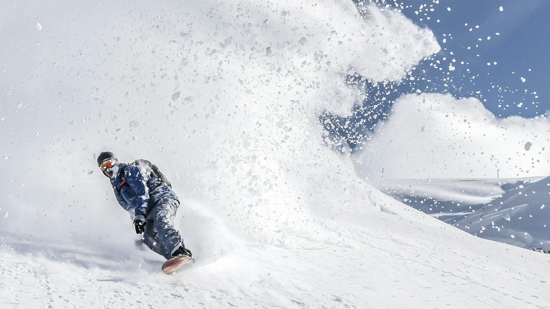 Snowboarder spraying large plume of powder.
