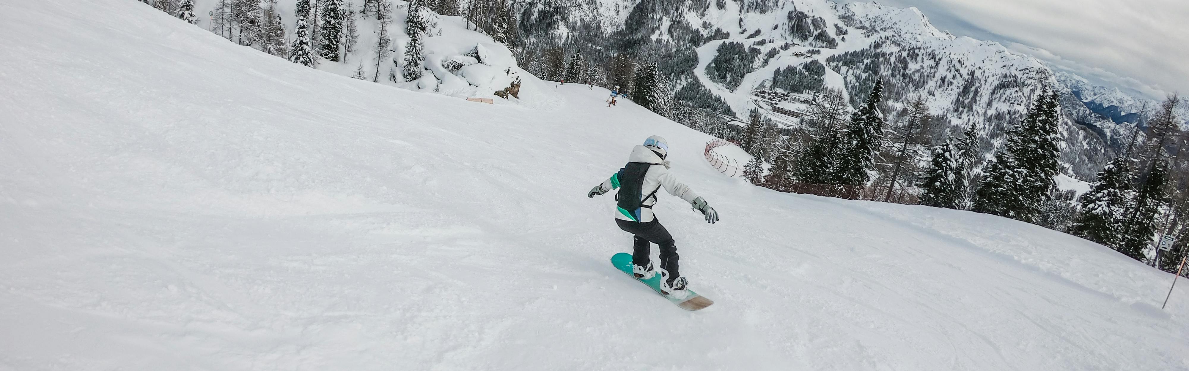 A woman snowboards carefully down a mountain