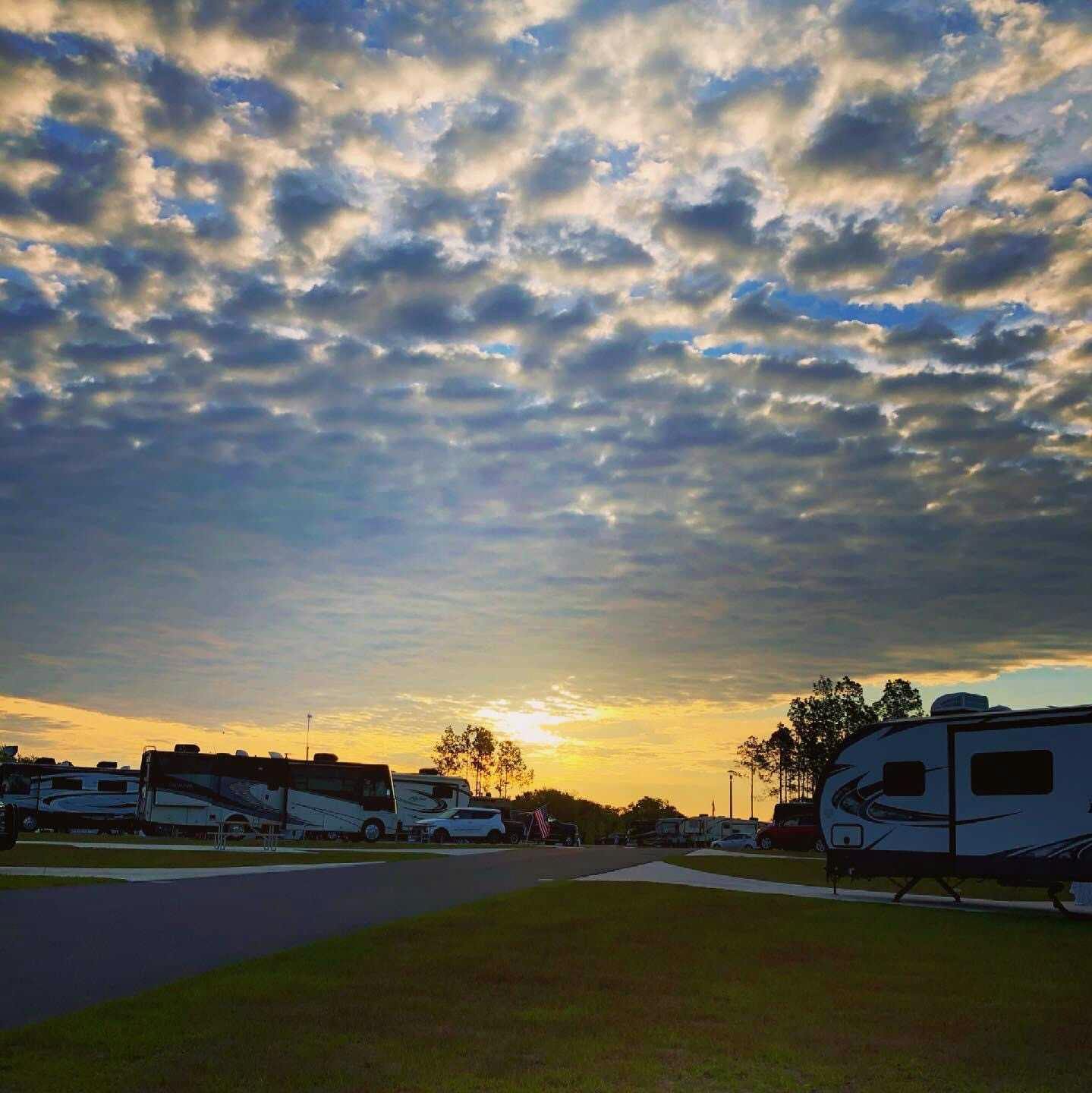 The sunset shines light on rippled clouds above an RV park.