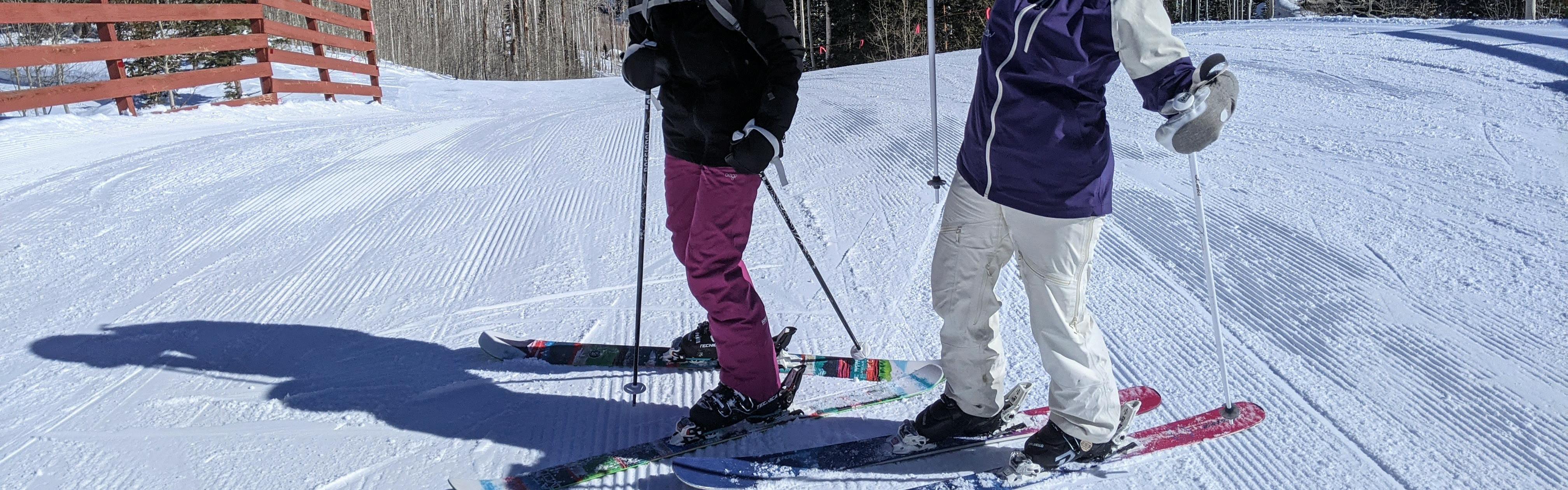 Two skiers standing on a groomed ski run. 