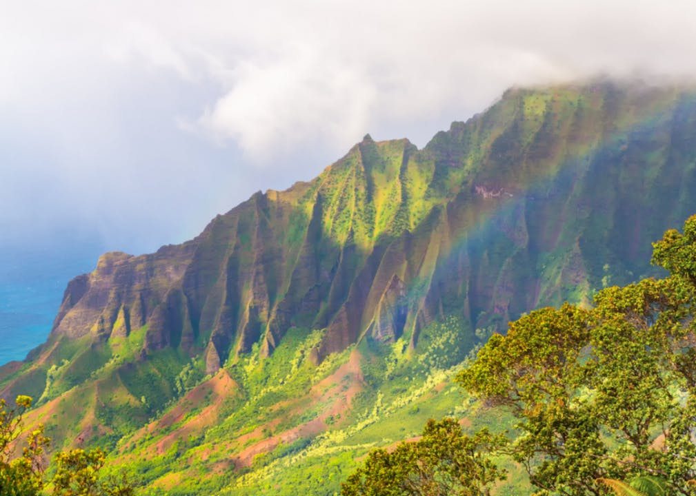 A rainbow on a bright cloudy day over the Napali Coast in Kauai