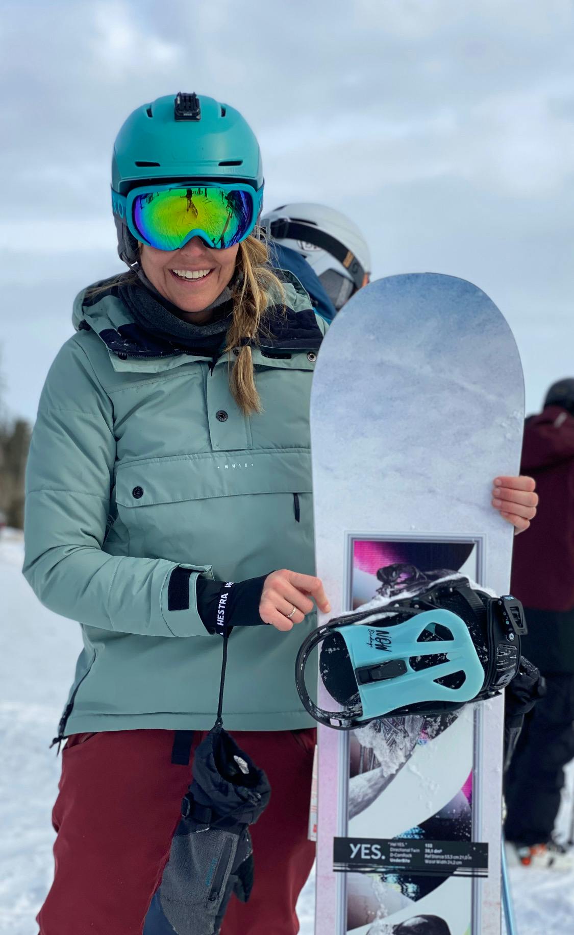 A woman standing next to a snowboard.