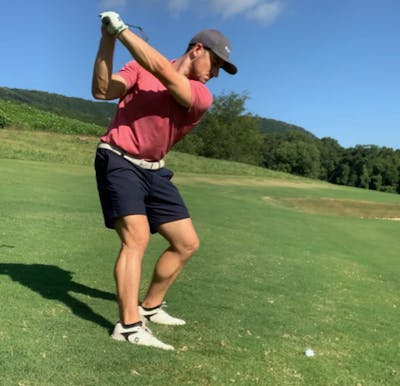 A man taking a swing with club at a Mizuno RB 566V Golf Ball.