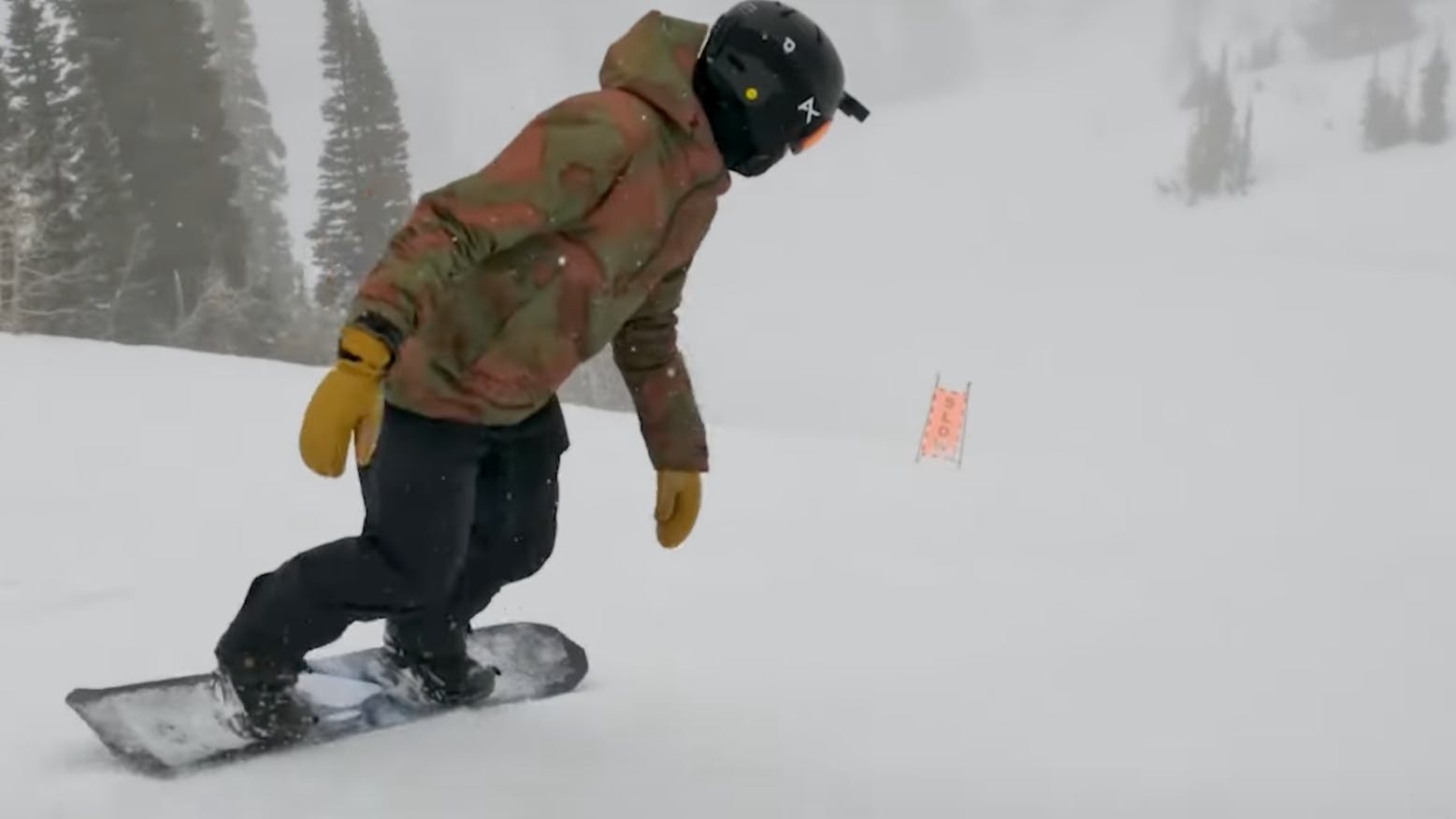 A snowboarder turning down the mountain on the Lib Tech Orca snowboard. 