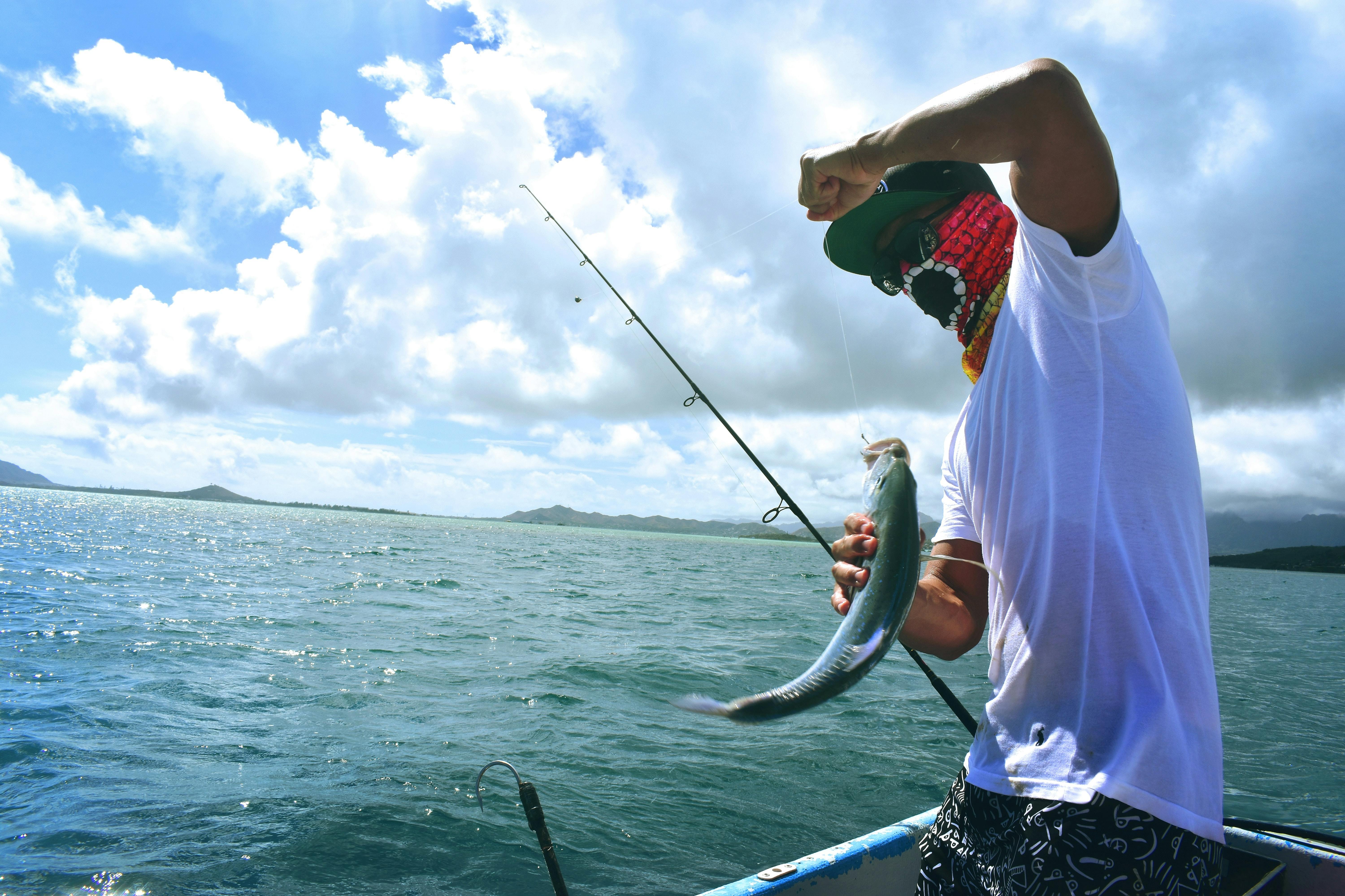 A saltwater fisherman holding up a line with a fish that he caught