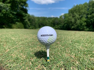A Callaway 2021 SuperSoft Golf Ball on a tee. There is a golf course in the background.