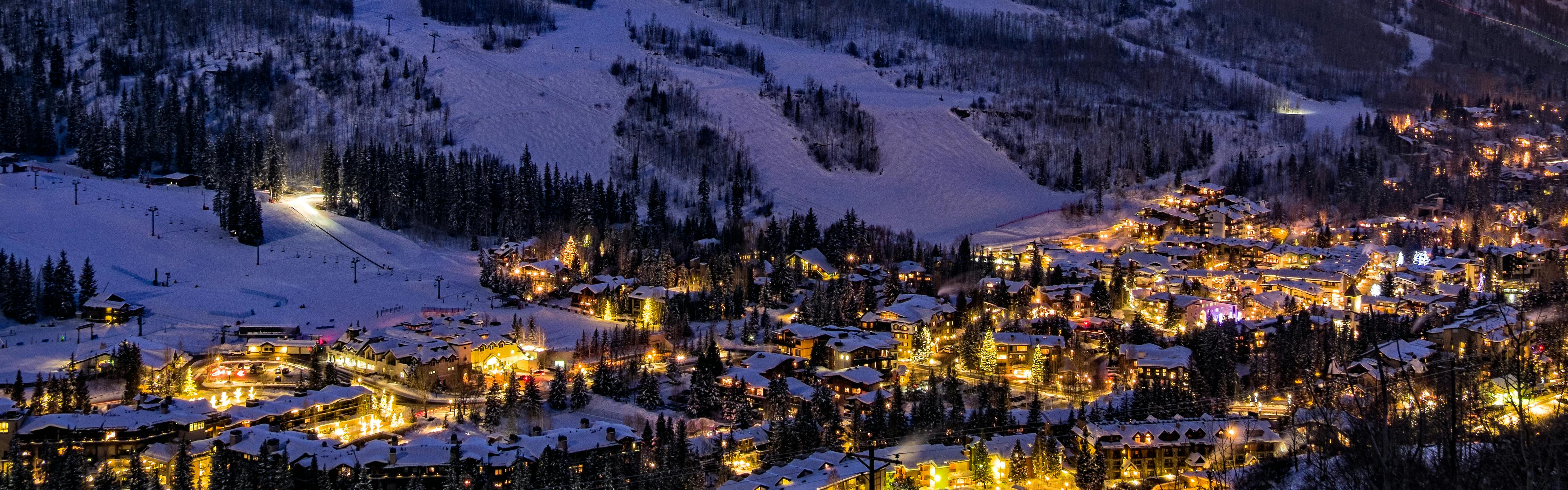 Houses and buildings at the foot of a ski hill lit up for the night
