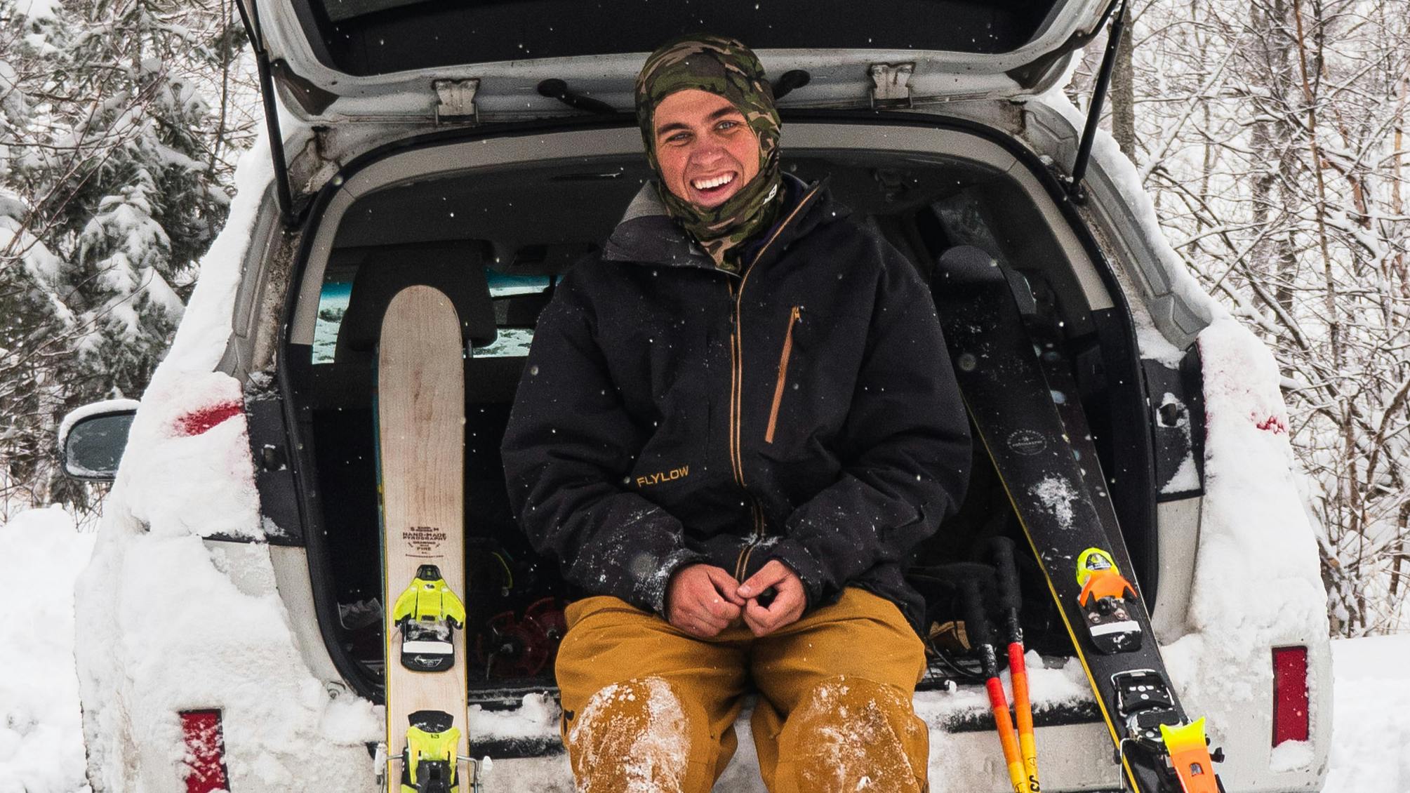 Curated expert Chris Goodhue sitting with two pairs of skis in the back of his van