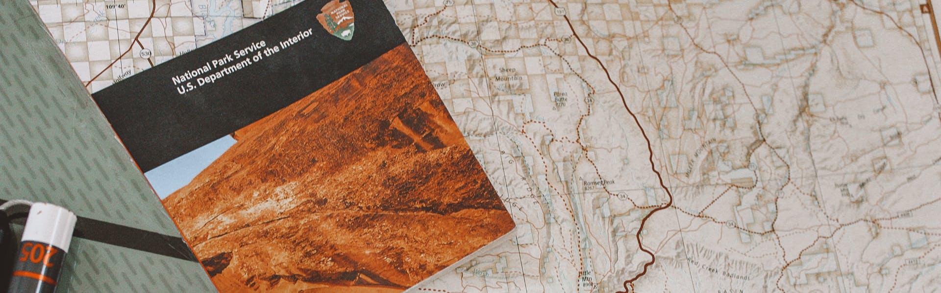 A close up of a map and a national parks brochure with a ski and a probe in the corner.