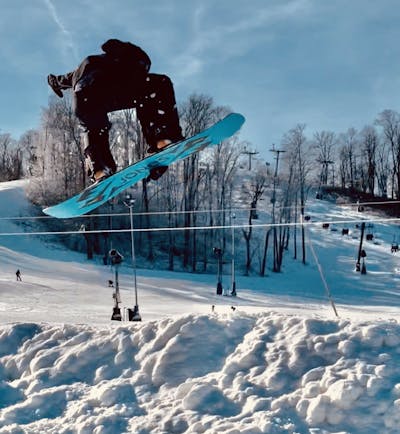 A snowboarder doing a jump on a Jones Mountain Twin Snowboard.