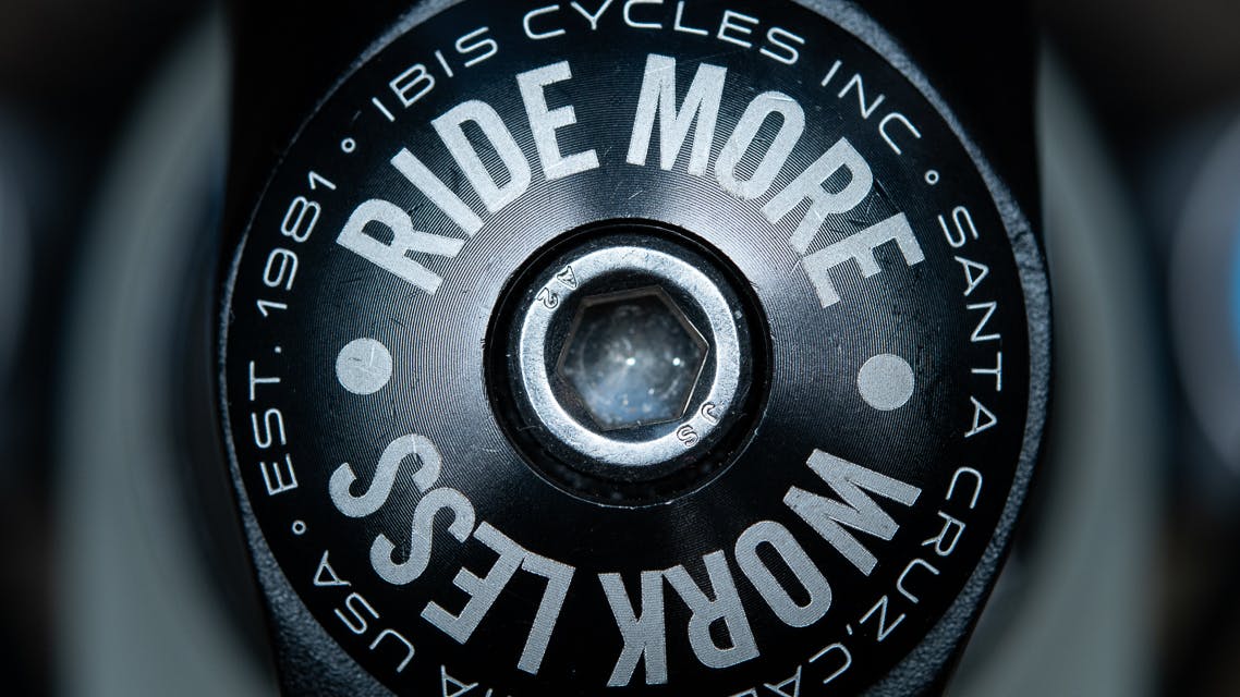 A closeup an Ibis Cycles' bike headset that says RIDE MORE, WORK LESS.