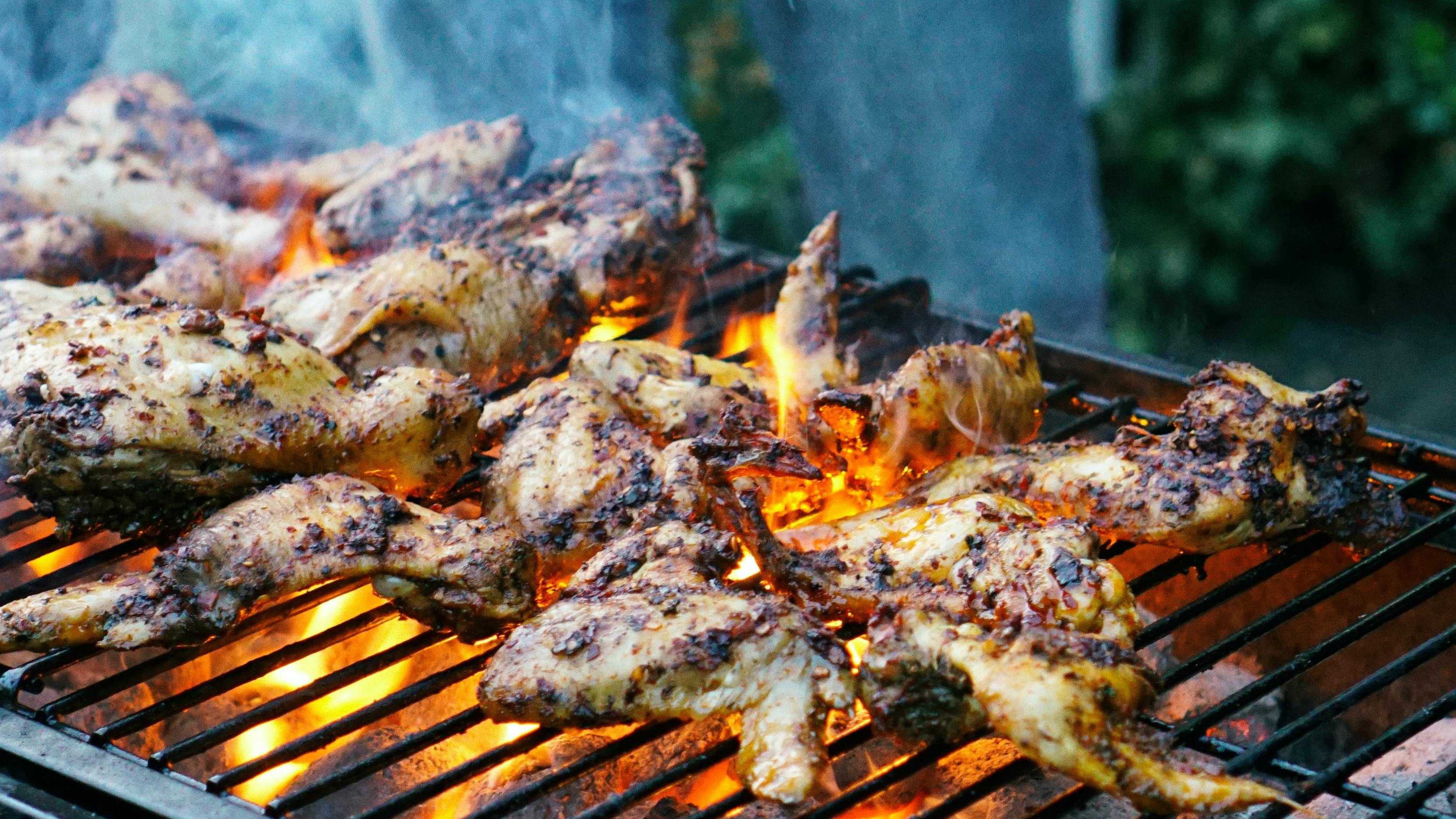 Some chicken cooking on a charcoal grill. 