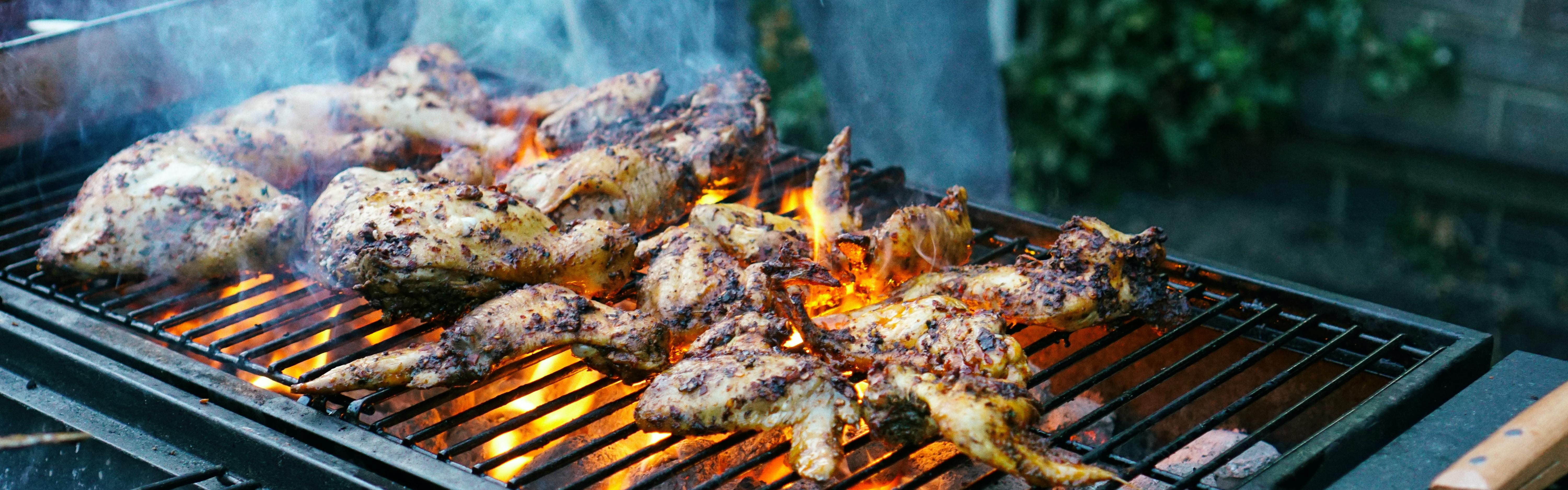 Some chicken cooking on a charcoal grill. 