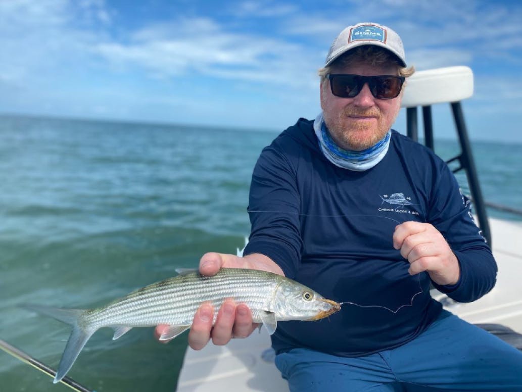 A man on a boat holding a bonefish.