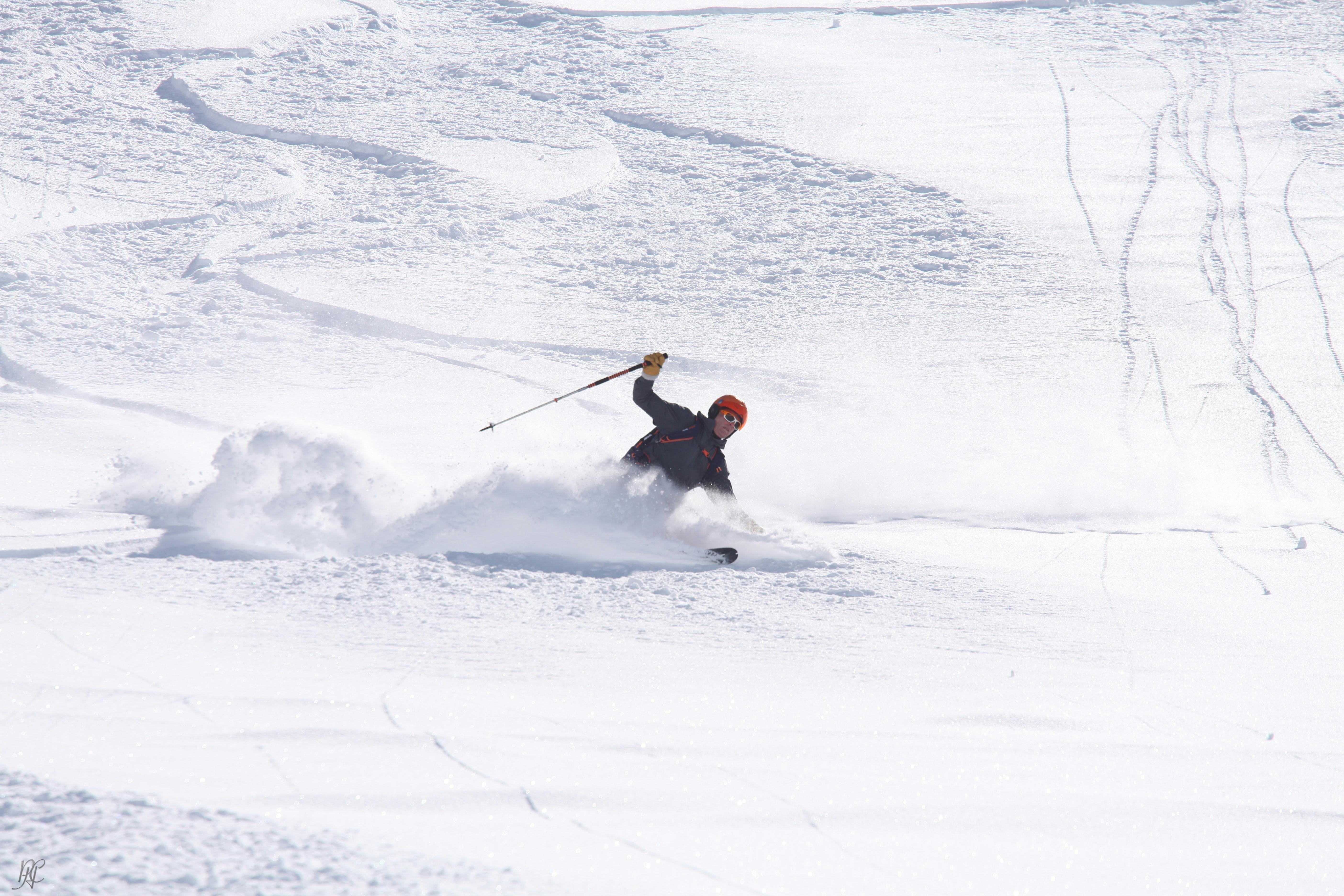 A skier turns in deep snow and kicks up a cloud of powder