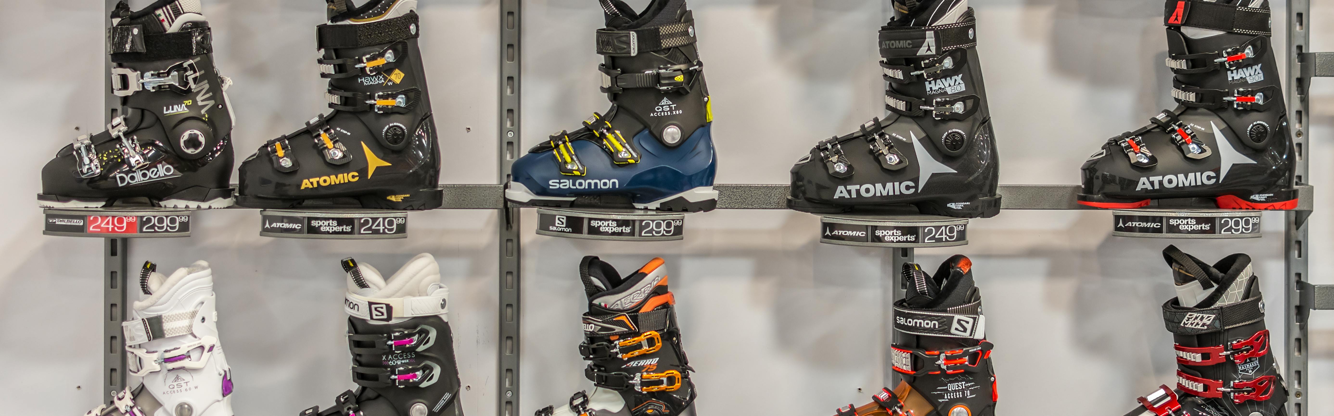 Several ski boots on a wall at a store.
