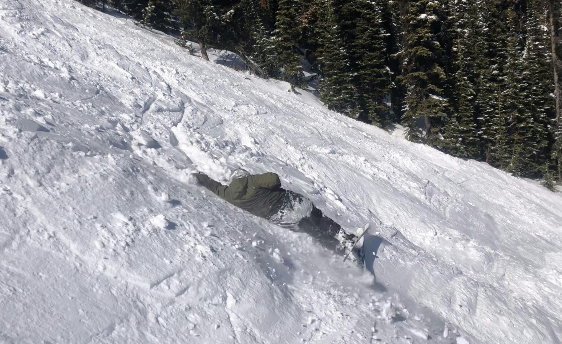 A snowboarder laying down on a snowy run. 