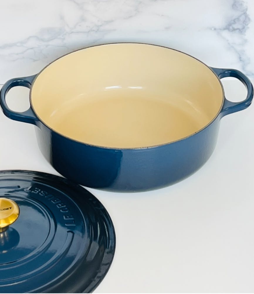 The inside of the Le Creuset 6.75 qt. Round Dutch Oven with the lid lying next to it. 