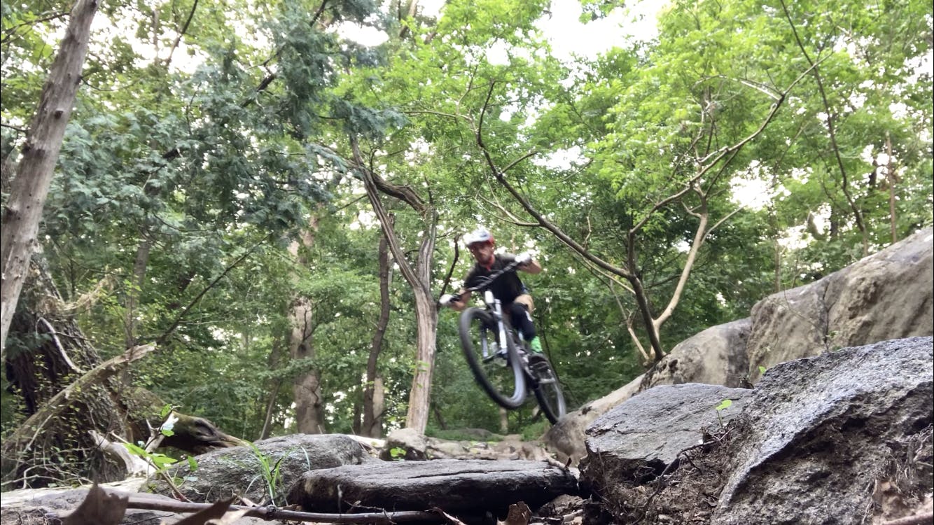 A biker bikes over some rocks.