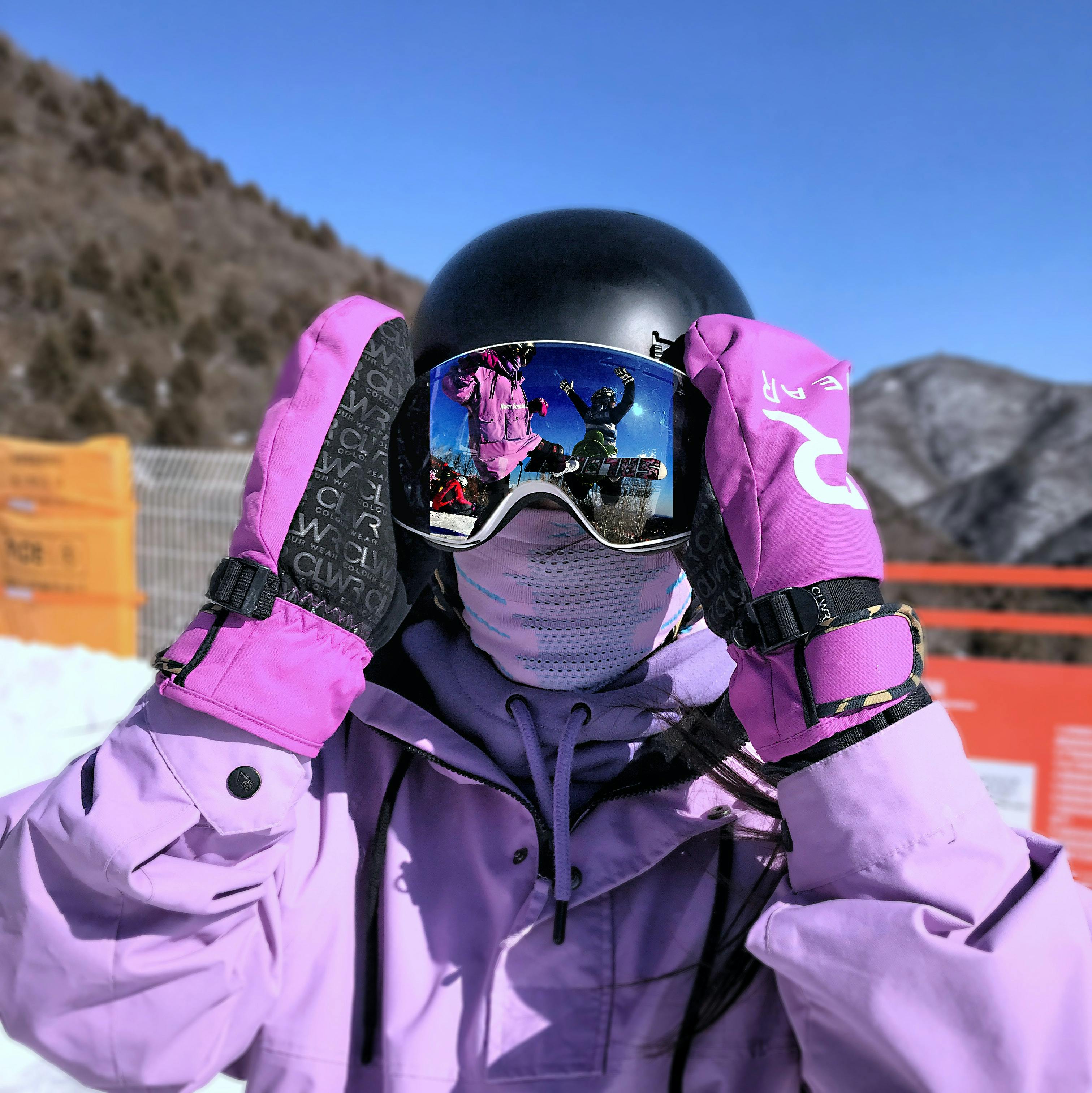 A boarder putting googles on over their helmet on the slope