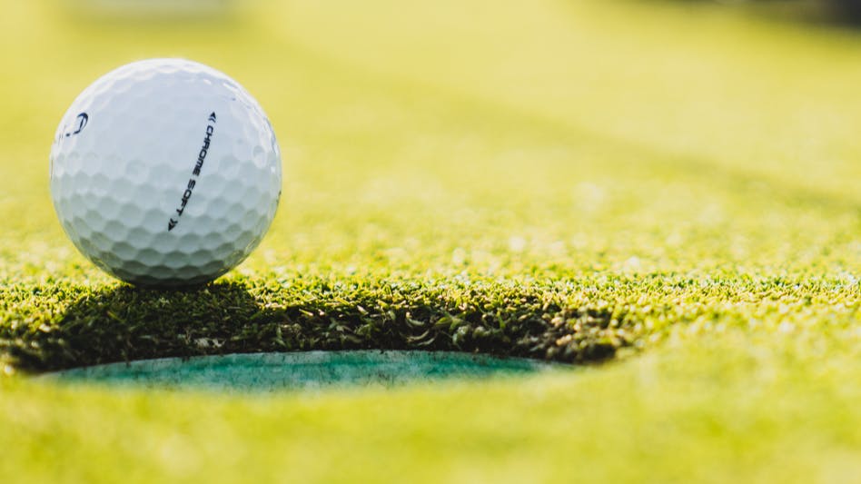 A golf ball on the edge of a hole on the golf course