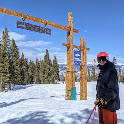 A skier standing under a sign that reads "Birds of Prey". He is wearing the Flylow Men's Knight Shell Jacket.  