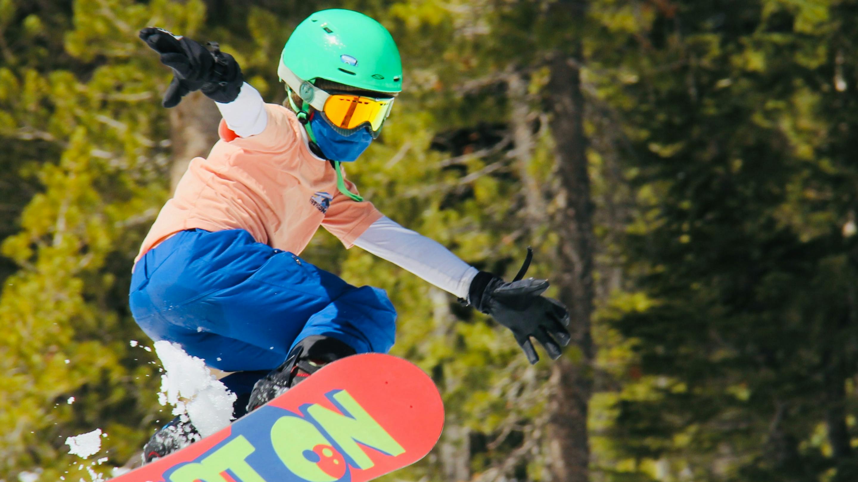 A young girl jumps with her Burton snowboard.