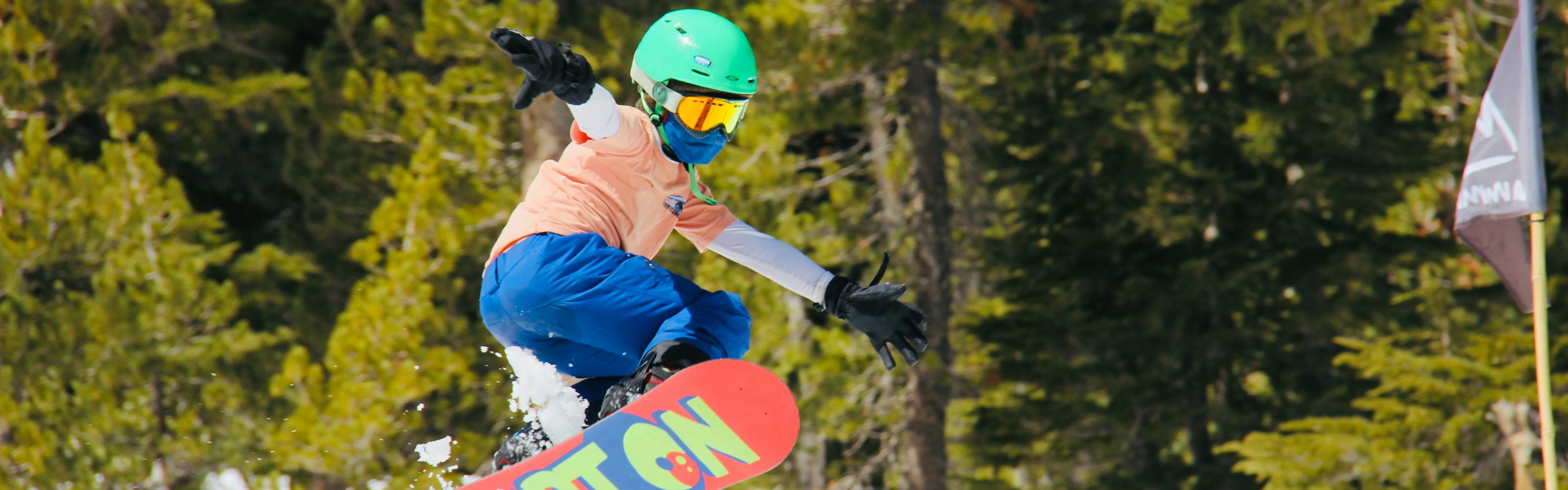 A young girl jumps with her Burton snowboard.