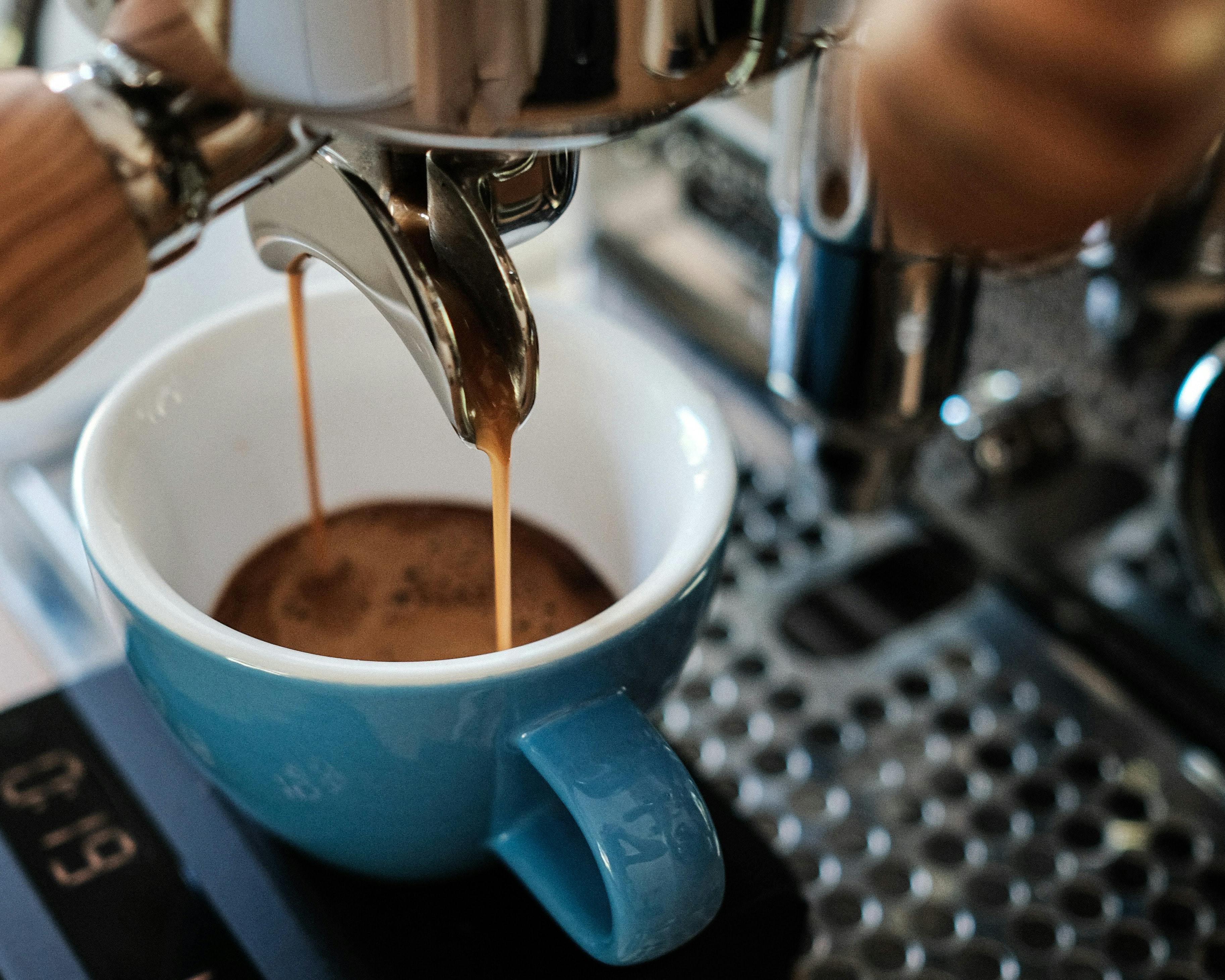 Espresso pours into a blue mug from a double-spouted portafilter. 