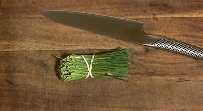 The Global Classic Chef's Knife next to some green onions. 