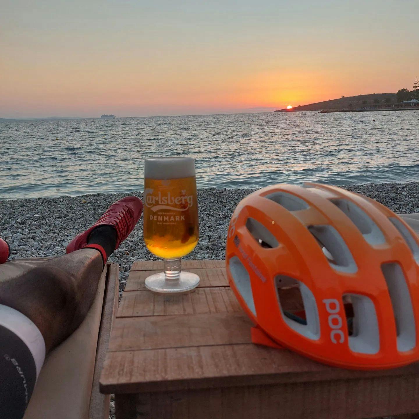 View of a beach, a beer, and a bike helmet. 
