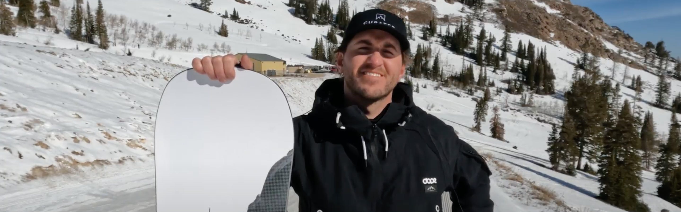 A man standing with the 2023 Never Summer Proto Ultra Snowboard.