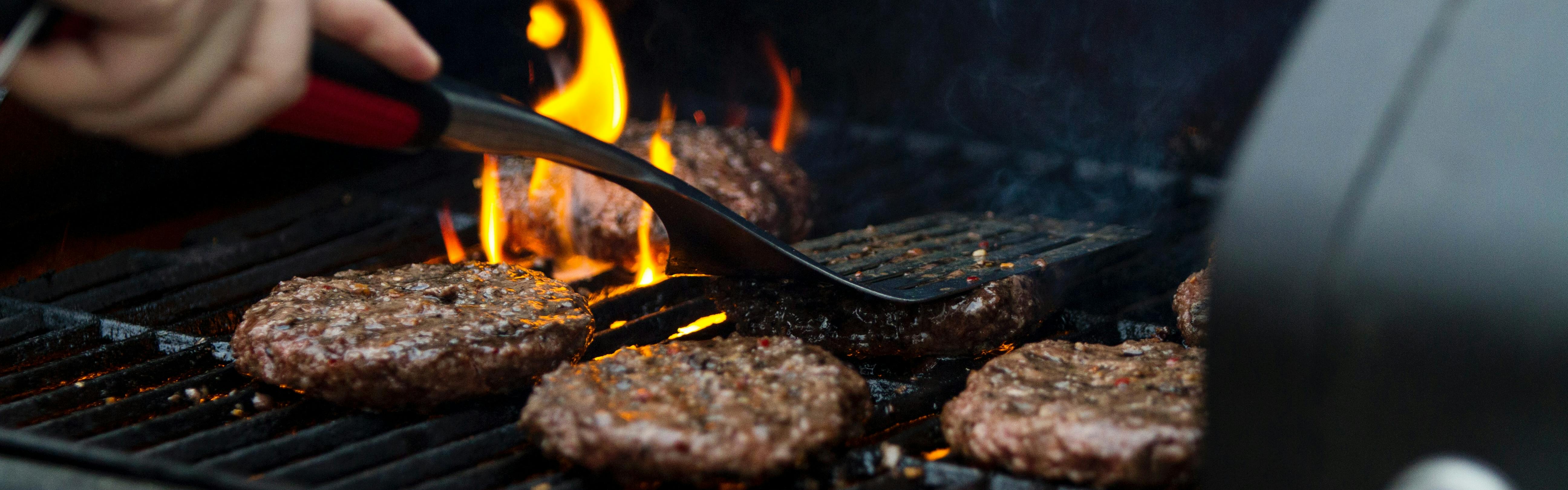 Burgers being grilled on a gas grill.