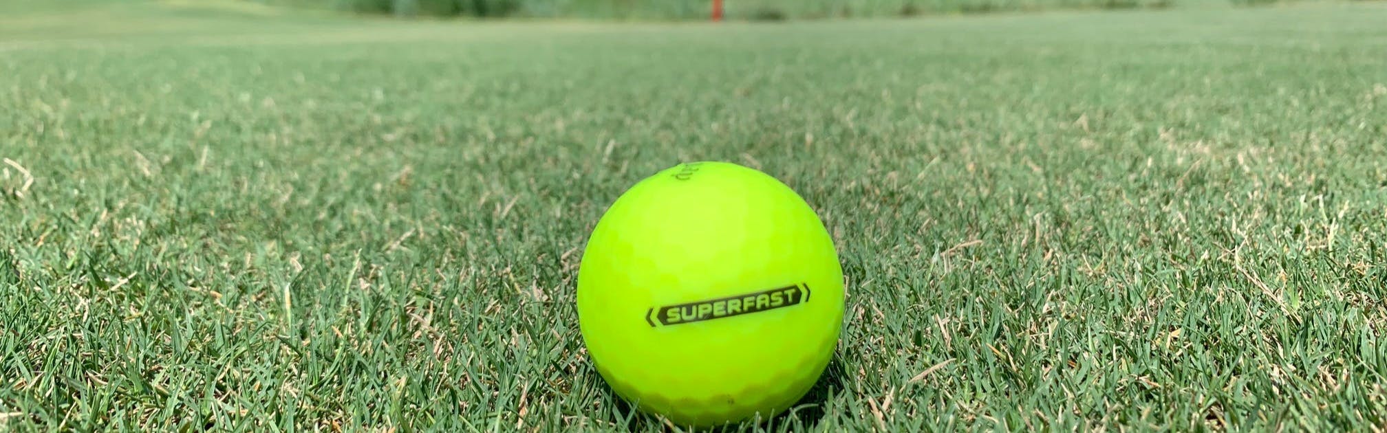 A Callaway Superfast BOLD Golf Ball sits on some grass.