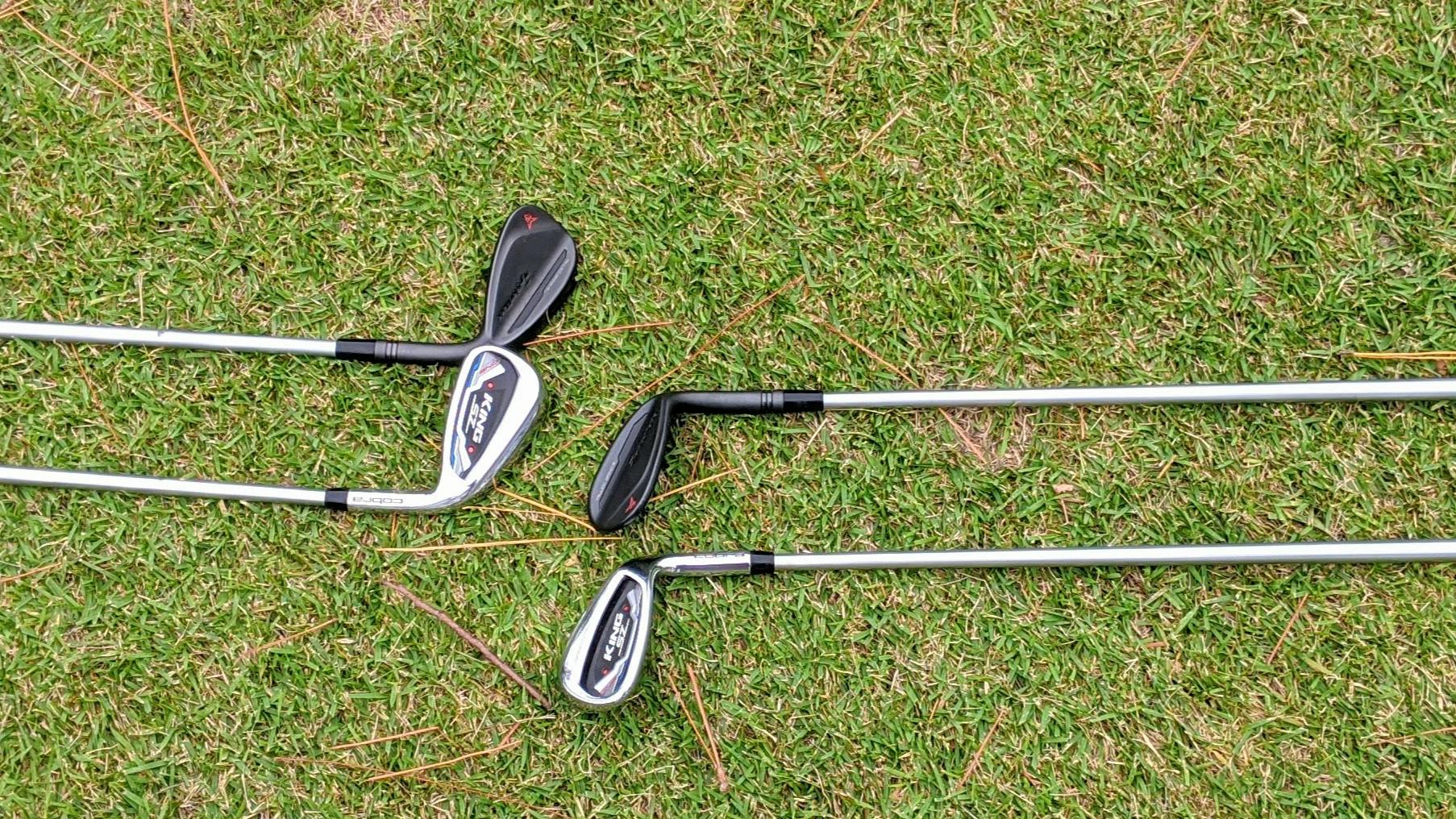 Four Cobra One-Length Irons laying in the grass